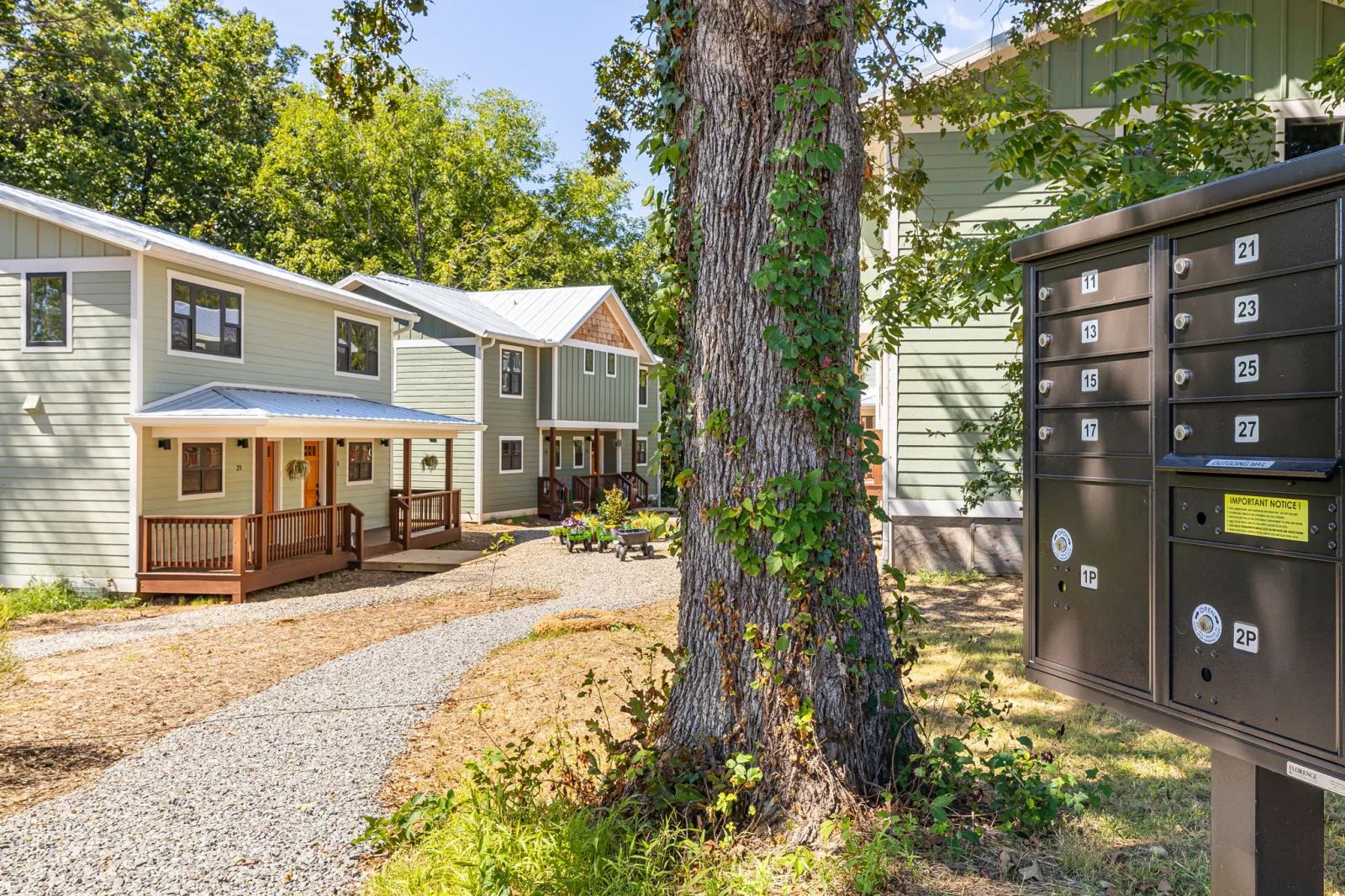 Terra Futura homes, a pedestrian path, a large tree, and the community mail kiosk